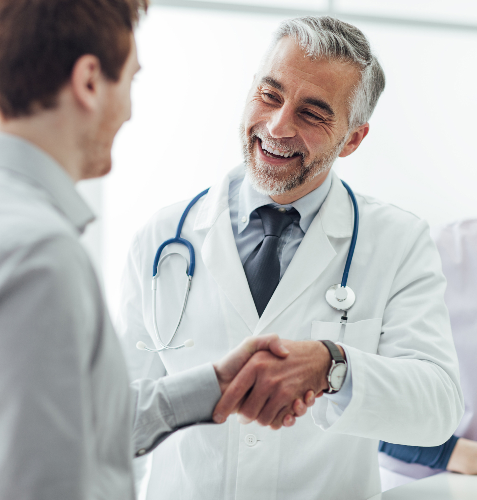 Photograph image of a friendly doctor shaking a patient's hand with a smile on his face.
