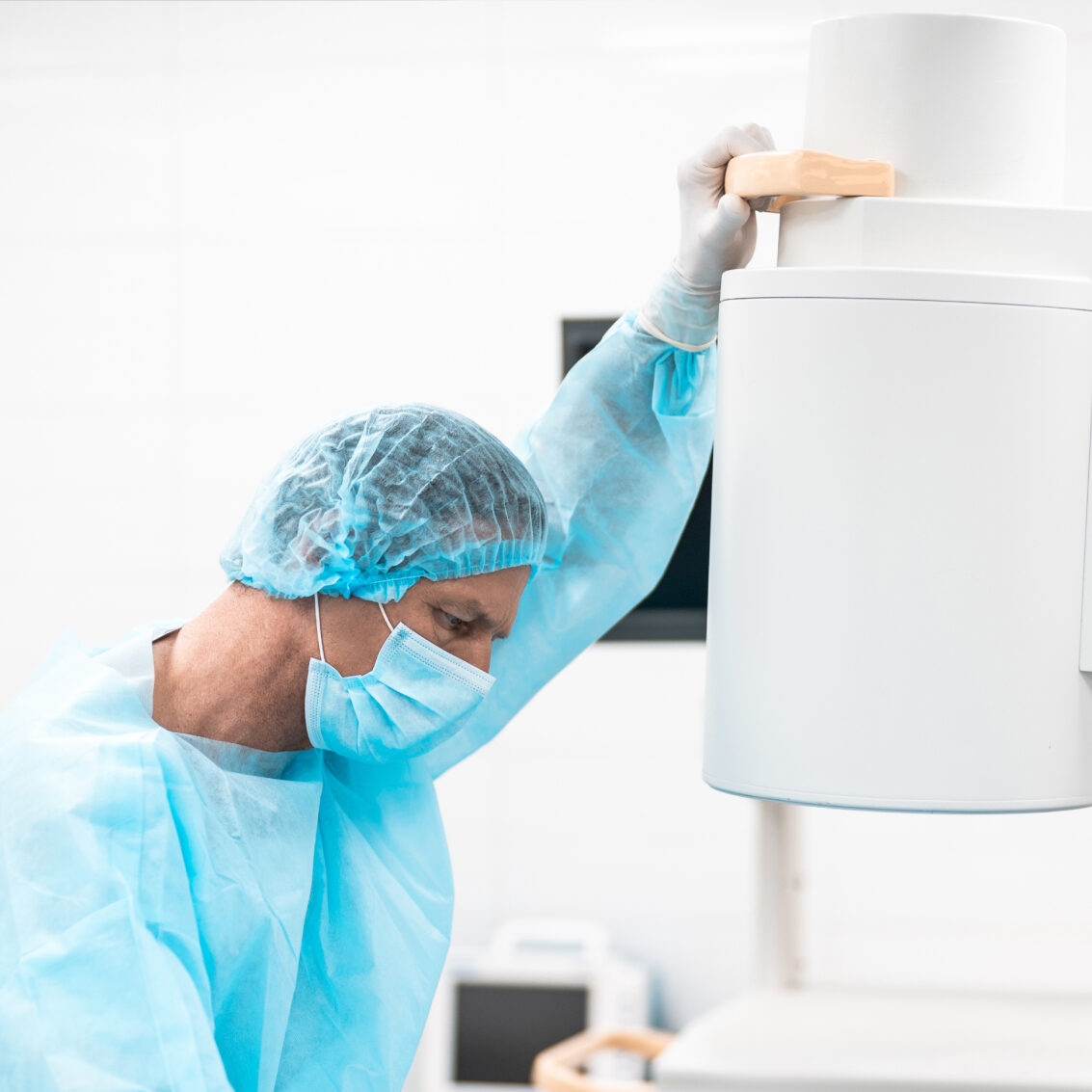 Photograph of a doctor in scrubs working in a surgical room with a C-Arm machine